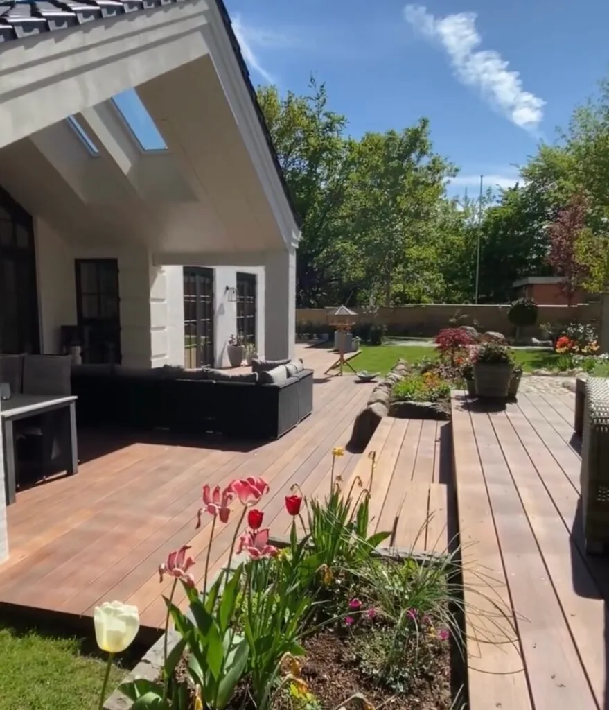 Moderne terrasse med blomster og solrig have